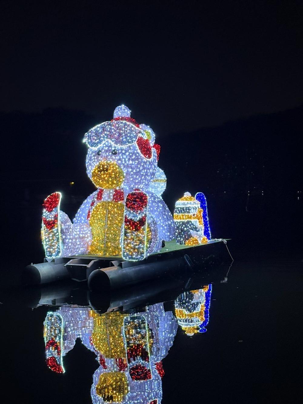 Glowing polar bear holiday display reflected on dark water