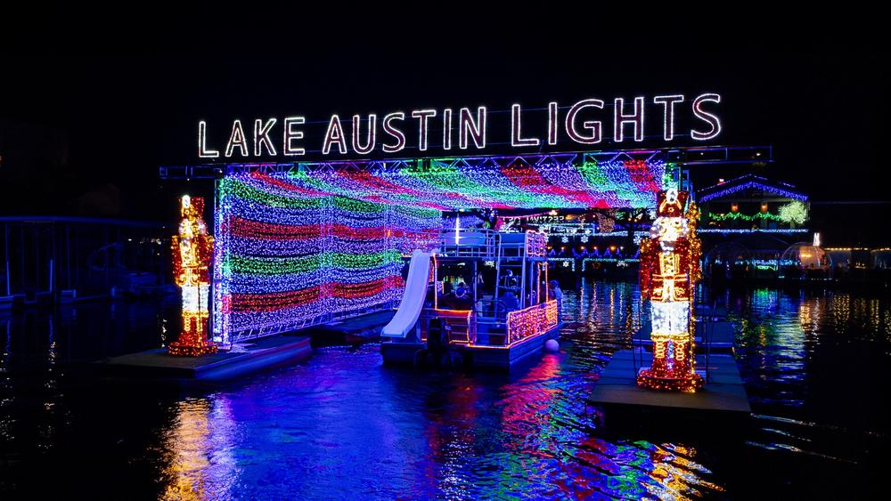 Illuminated Lake Austin Lights tunnel with a holiday boat and colorful reflections