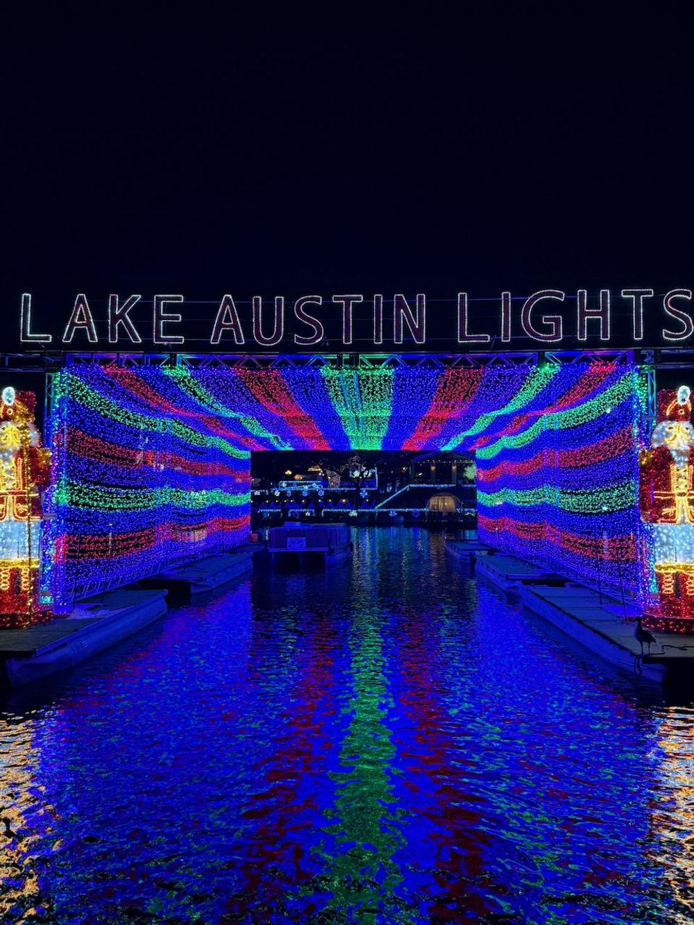 The floating light tunnel viewed straight on, its colors reflected in Lake Austin