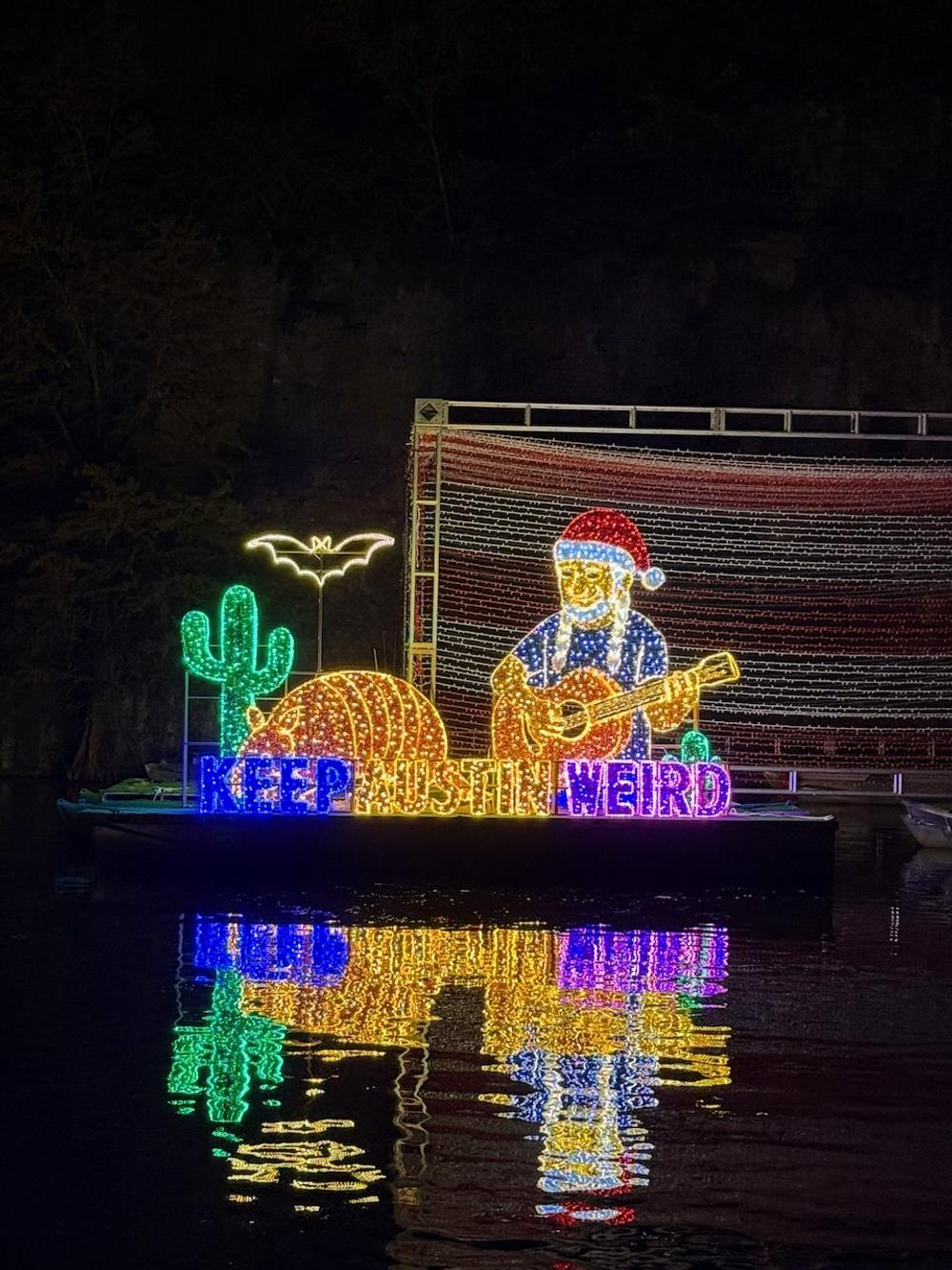 Illuminated Texas musician and armadillo display reflected in the lake